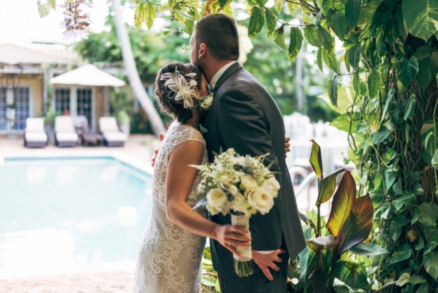 Bride and groom’s portrait under palm trees at Hotel Escalante, Naples wedding