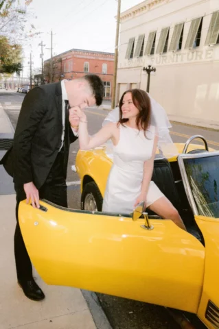 Chic Tampa Wedding Vibes – Stills by Hernan Editorial Fine Art Photography Bride and groom sharing a playful moment beside a classic yellow convertible at Hotel Haya, Tampa, captured by the renowned Stills by Hernan