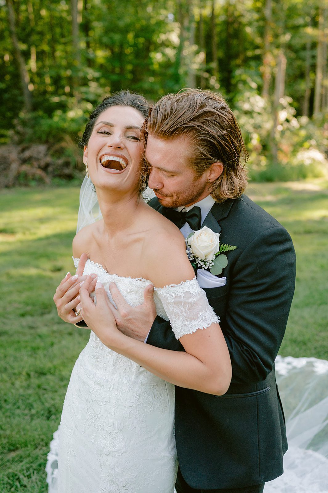 Bride laughing while groom embraces her from behind