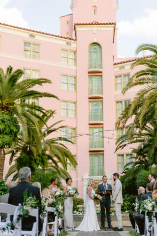 Outdoor Wedding Ceremony at The Vinoy in Downtown Saint Petersburg, Florida Elegant outdoor wedding ceremony at The Vinoy in downtown Saint Petersburg, Florida, featuring the bride and groom exchanging vows under palm trees with the iconic pink hotel backdrop